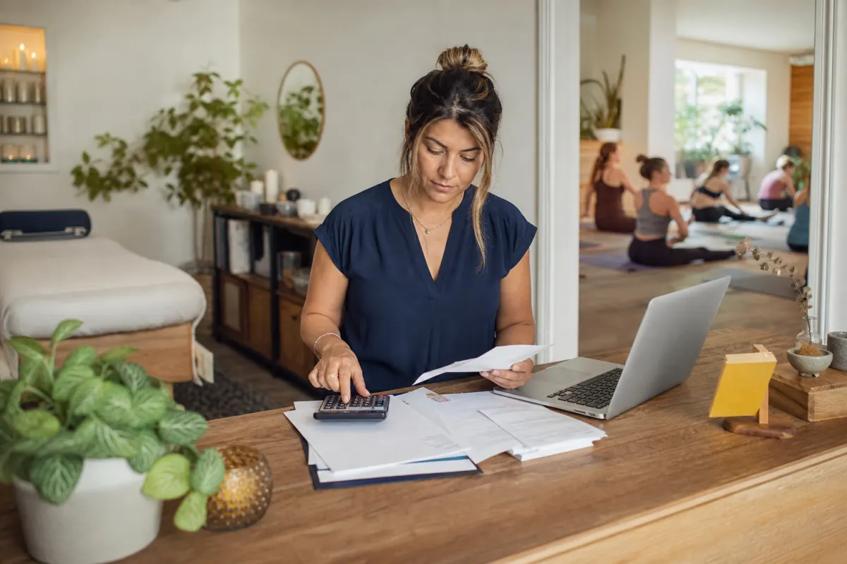 Wellness center owner auditing merchant fees at a calm reception desk