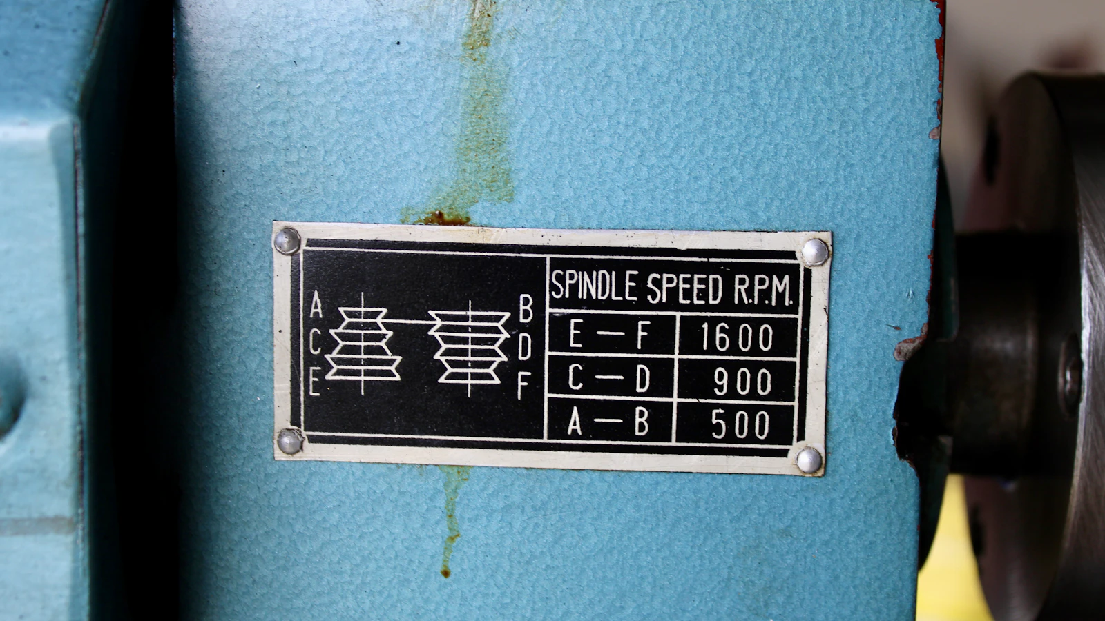 A spindle-speed reference plate on the blue housing of a machine tool.