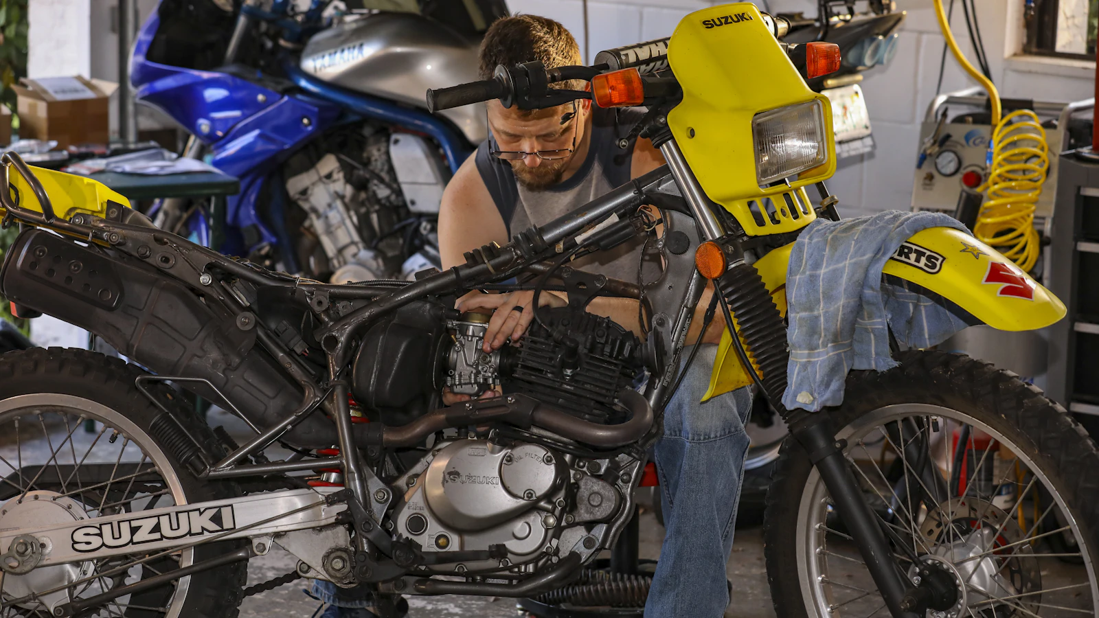 A mechanic working on a motorcycle engine in a workshop.
