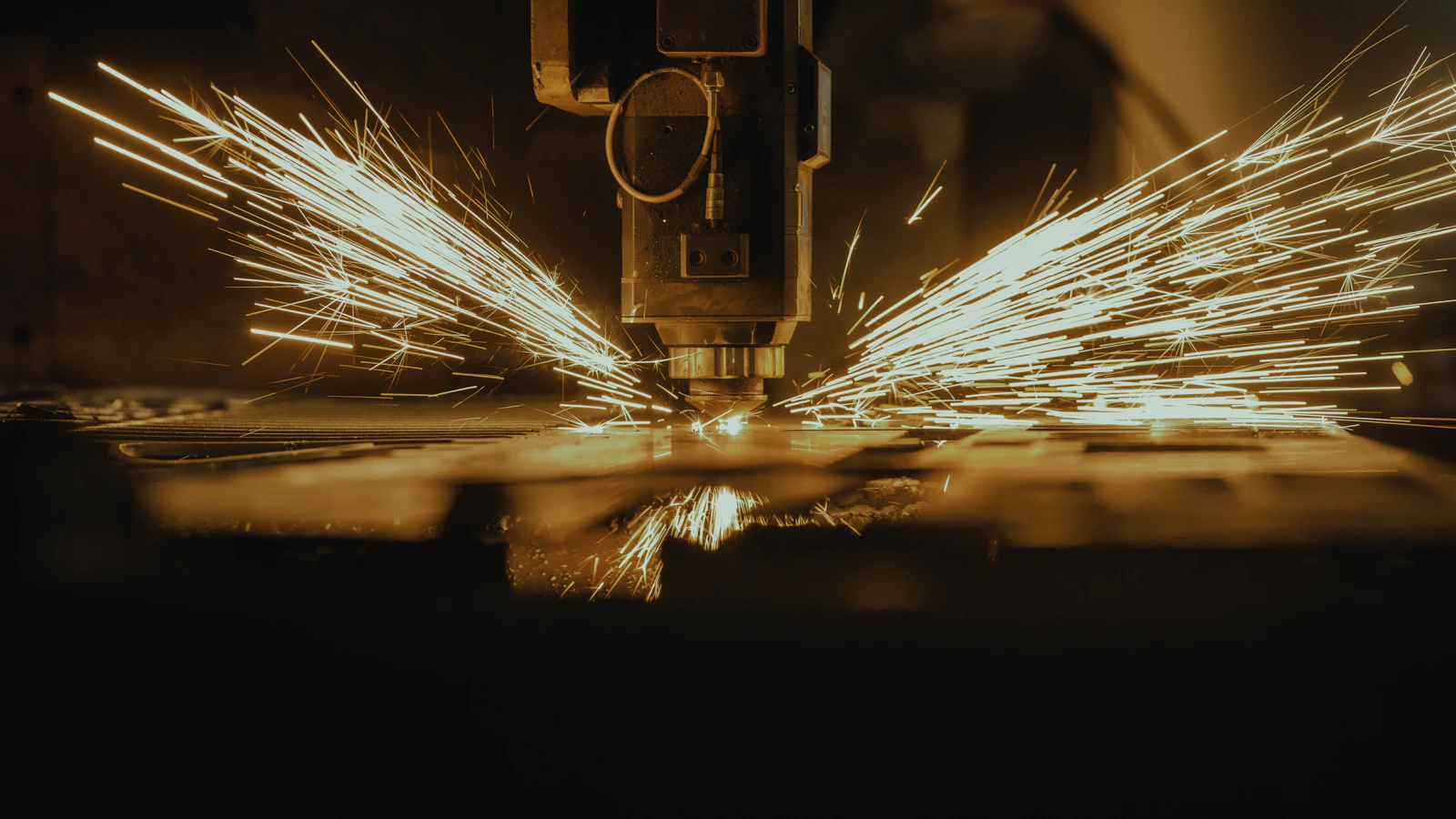 A machine cutting metal with sparks spreading across the work surface.