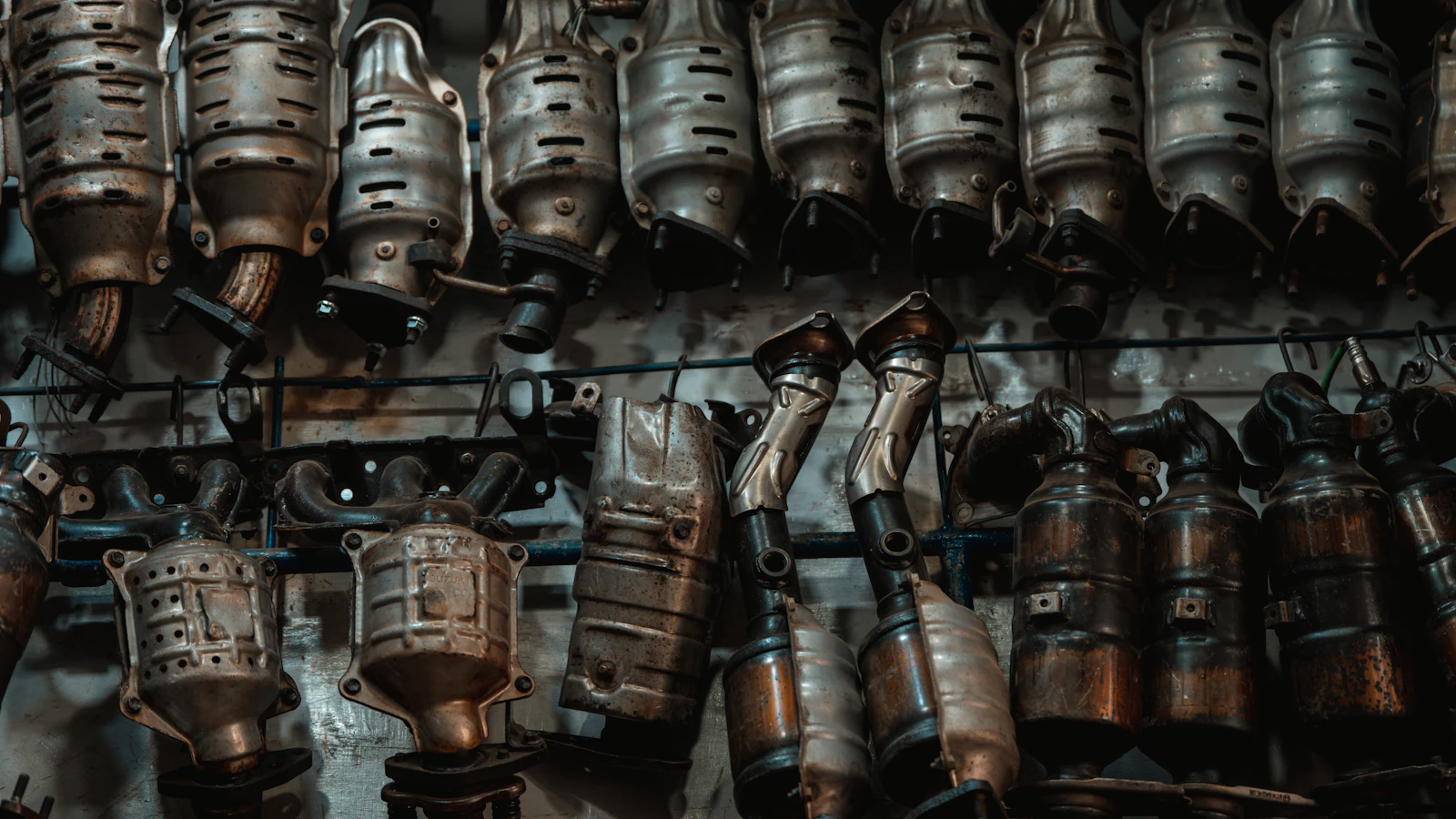Metal exhaust components hanging along a workshop wall.