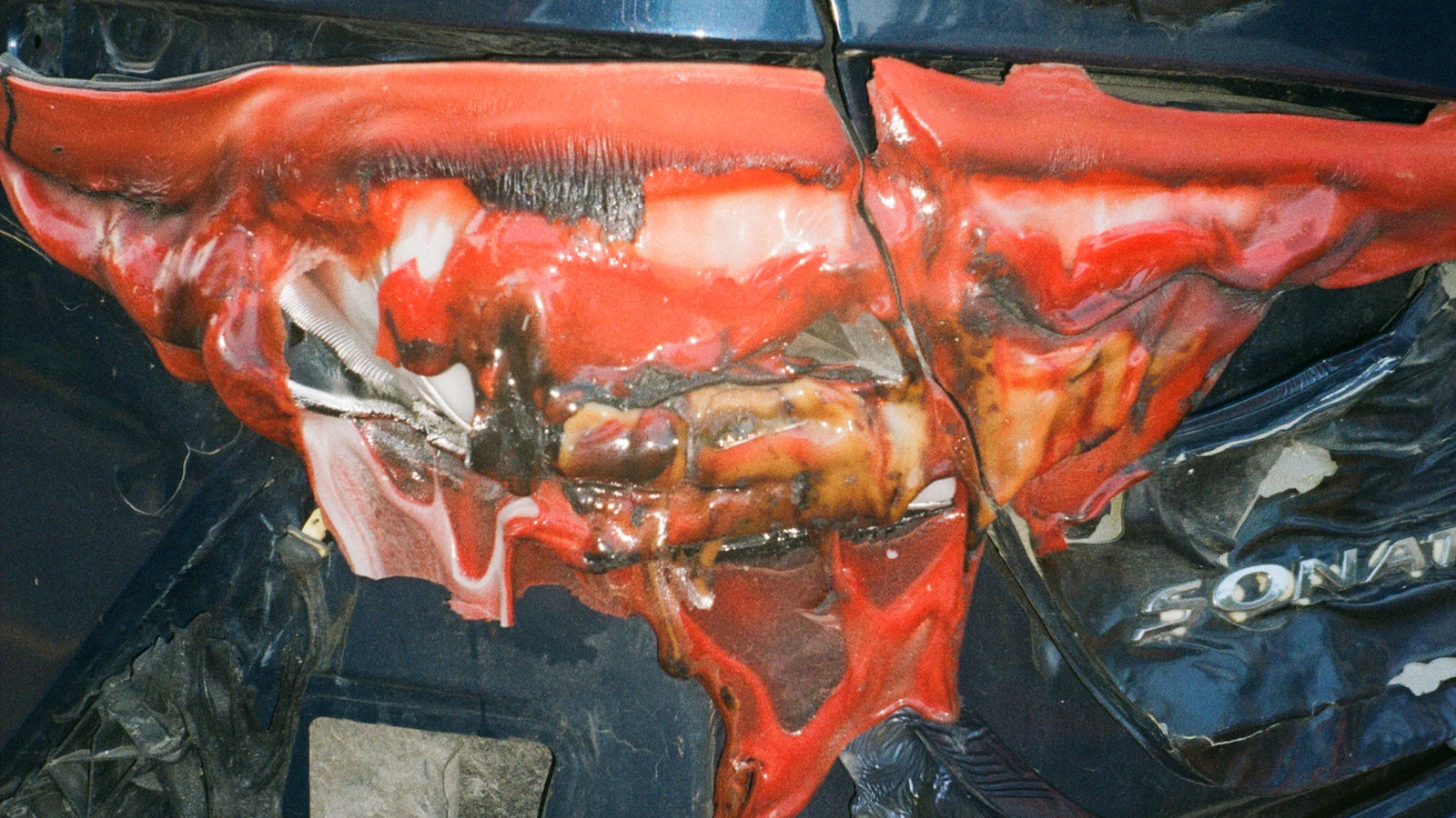 A red vehicle with a crushed front panel and exposed damage.