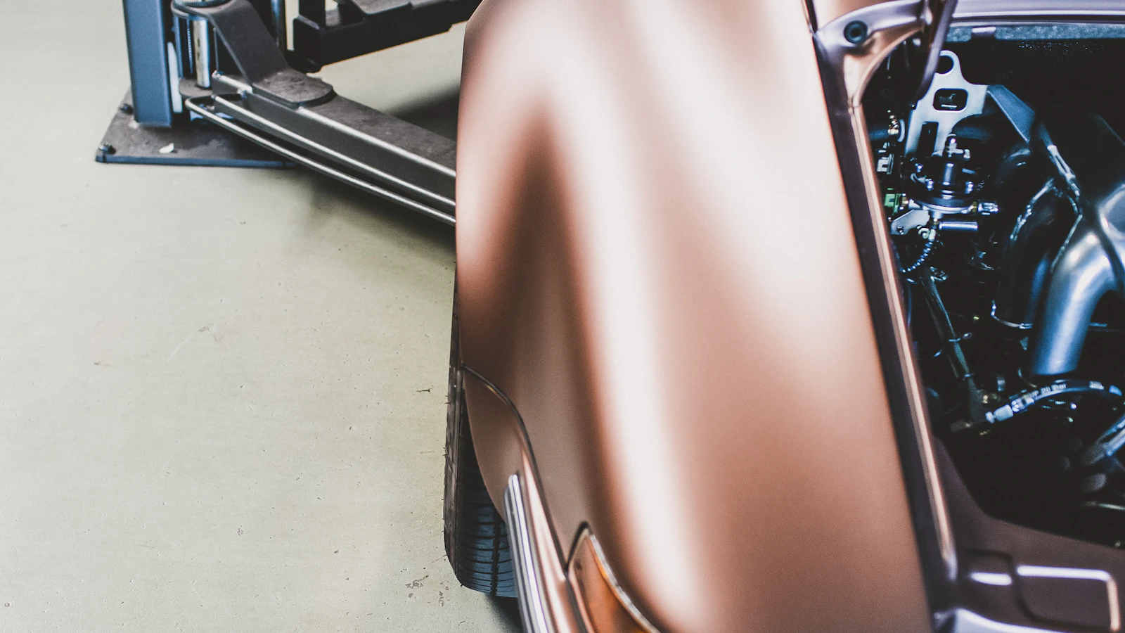 A brown vehicle fender and exposed engine area inside a workshop.