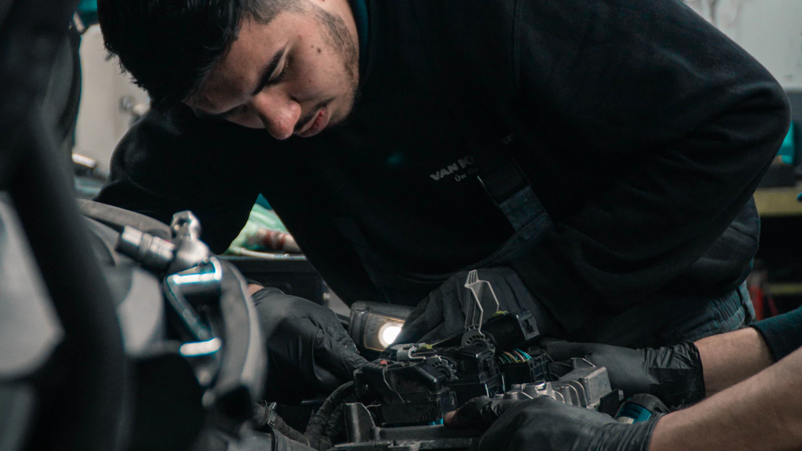 A person leaning over an engine compartment while working on vehicle components.