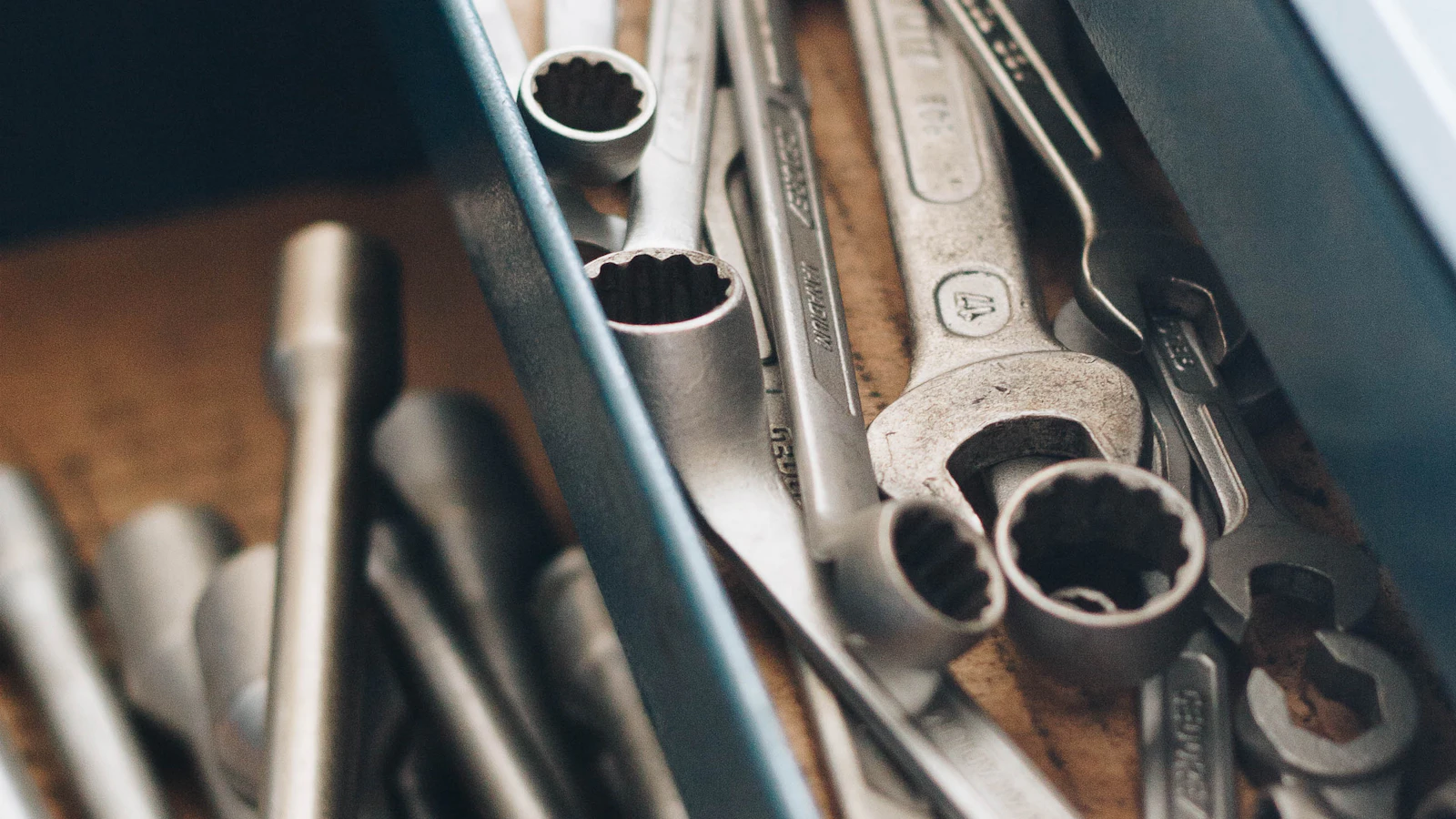 Wrenches and other metal hand tools in a workshop tray.