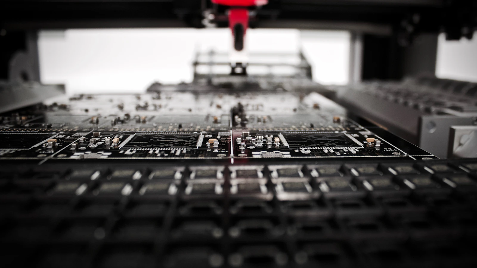 An automated workstation positioned above rows of electronic circuit boards.