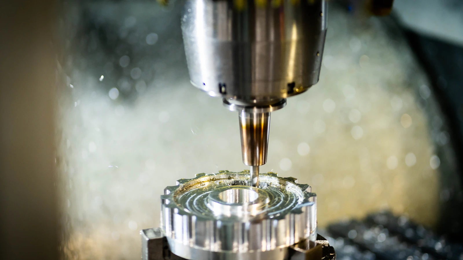 A machining spindle working above a metal component with visible coolant.