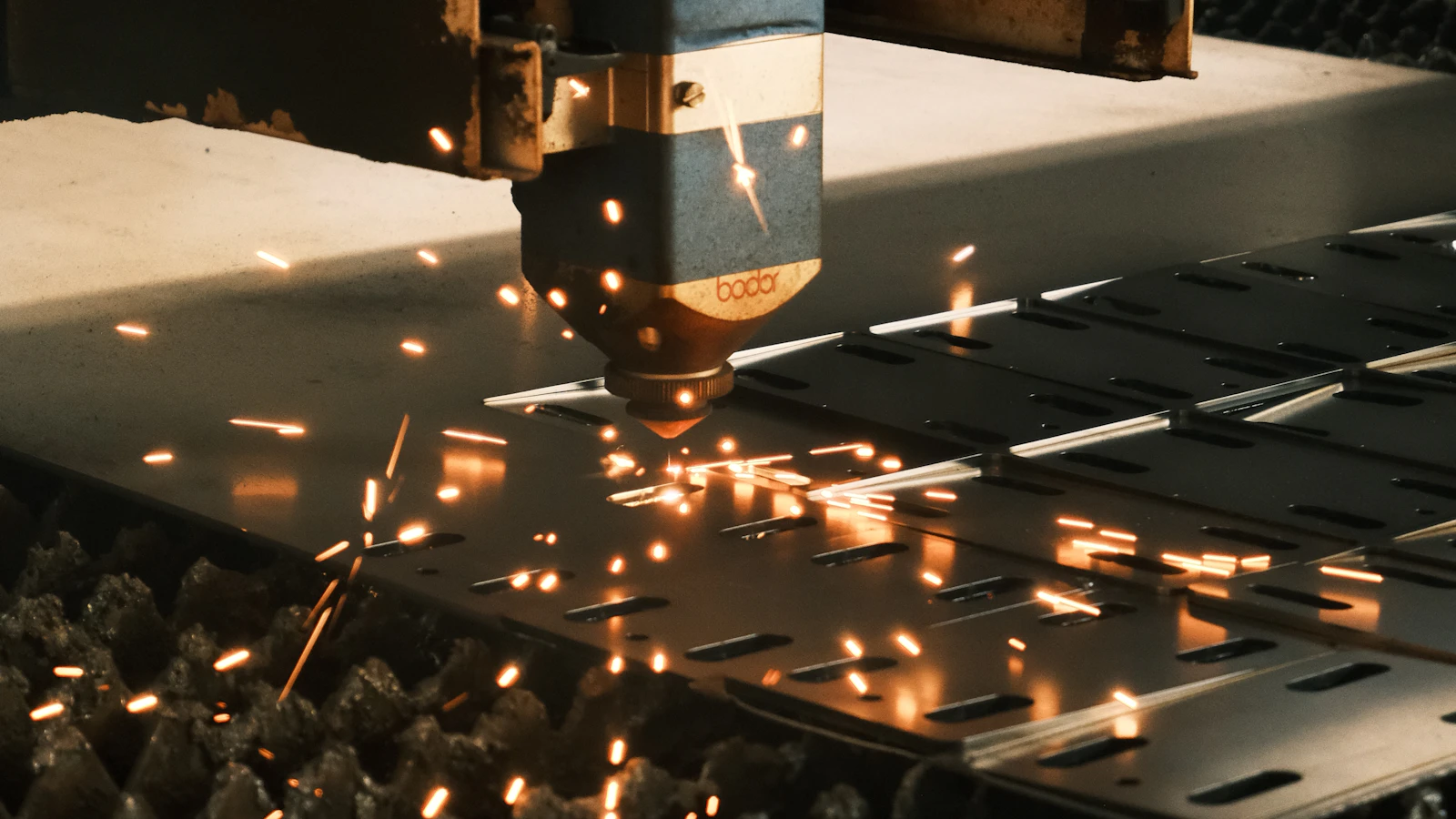 Sparks around a machine cutting a flat metal sheet.