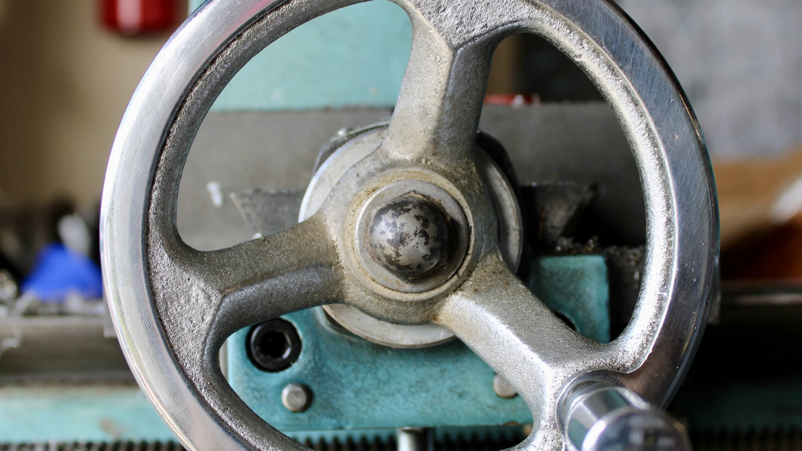 A close view of a metal handwheel on a green machine.