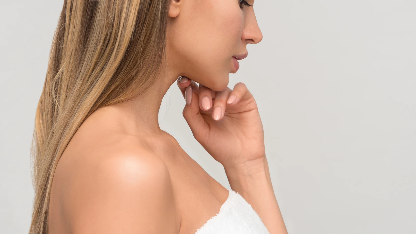 A person wearing a white towel with a hand near their chin.