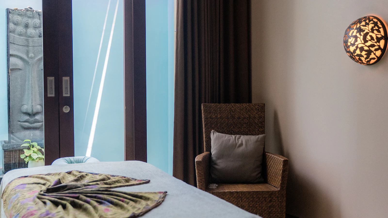 A spa bed with a decorative leaf beside a chair and window.