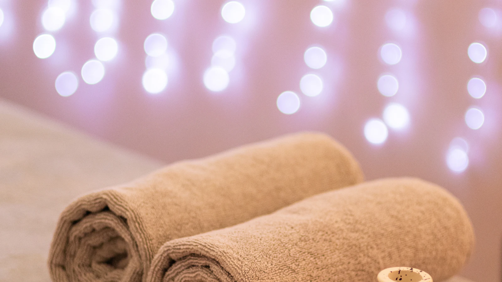 Two rolled towels beneath soft lights in a spa setting.
