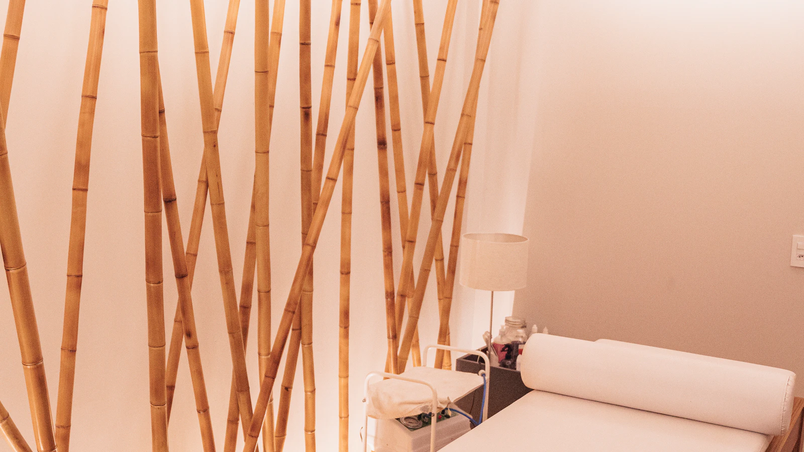 A white treatment bed beside a vertical wooden partition.