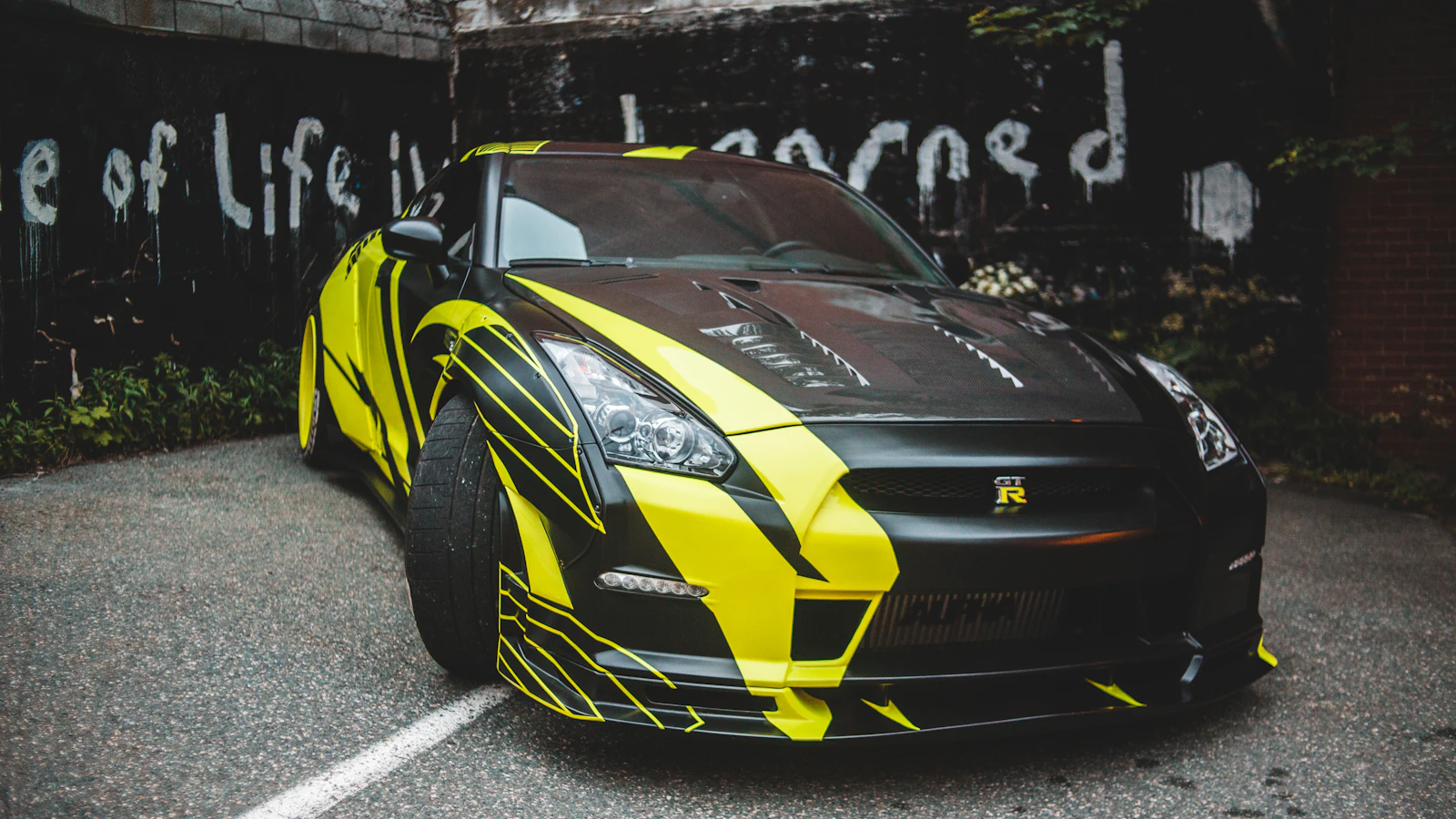 A black and yellow vehicle with graphic patterns parked on pavement.