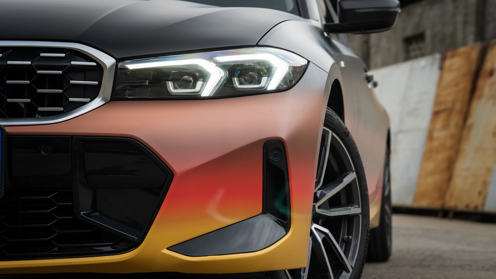 The front of a vehicle with a multicolor gradient finish inside a workshop.