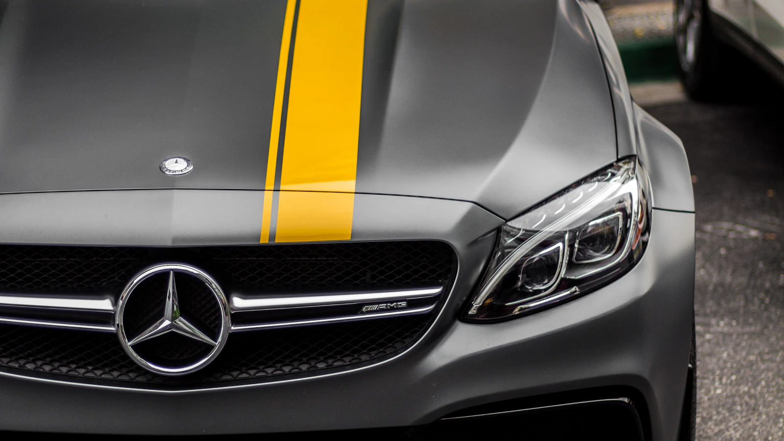 The front of a gray vehicle with a yellow stripe across its hood.