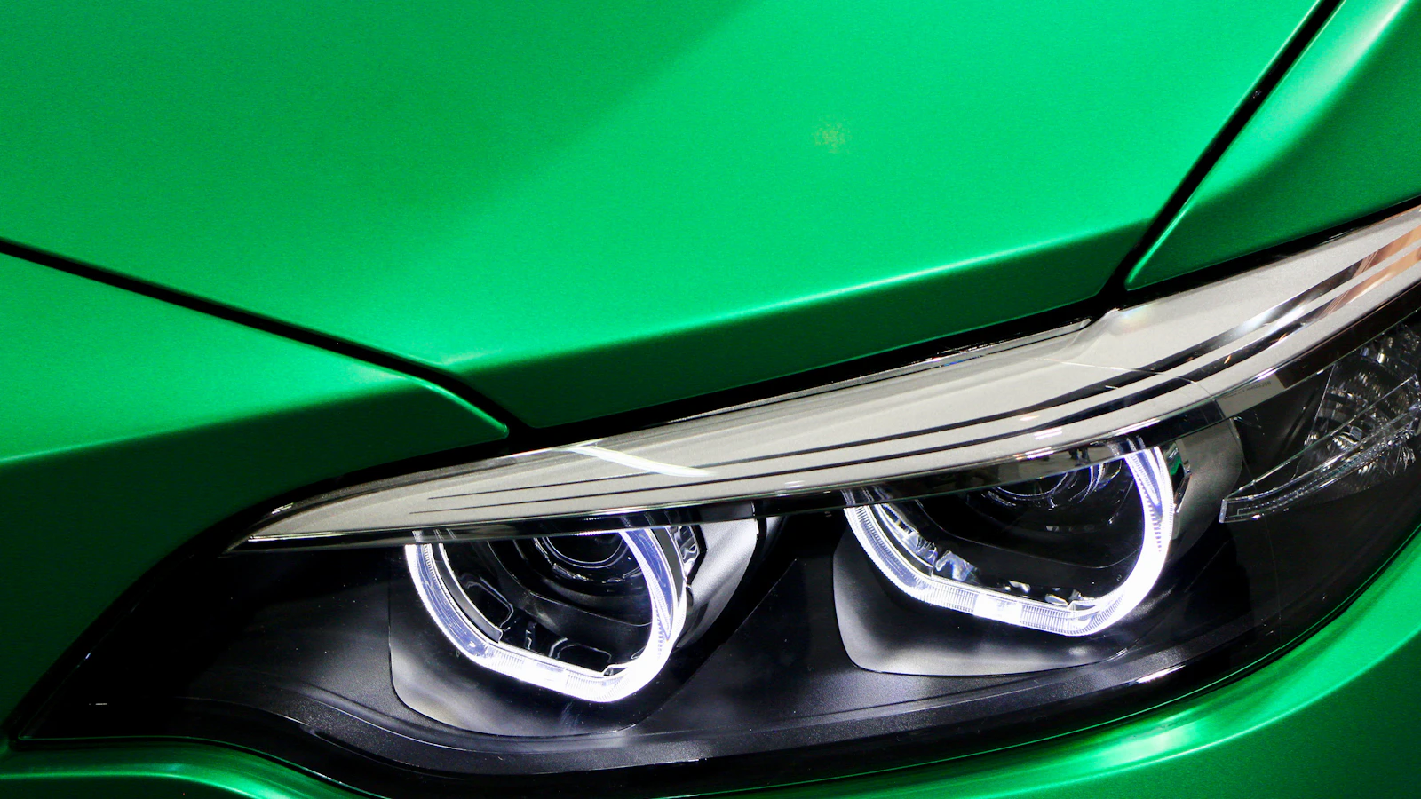 A close view of the headlight and green front panel of a vehicle.
