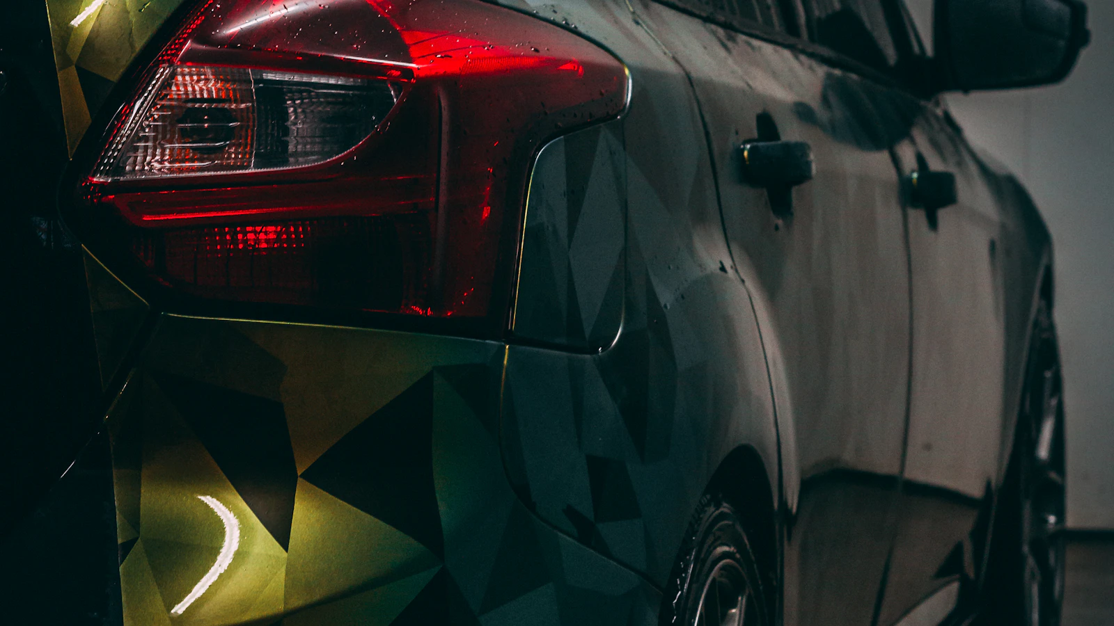 The rear corner of a dark vehicle with geometric colored graphics.