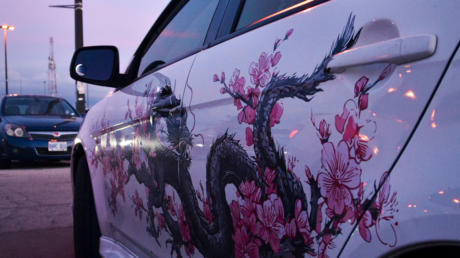 The side of a white vehicle with dragon and pink blossom graphics.