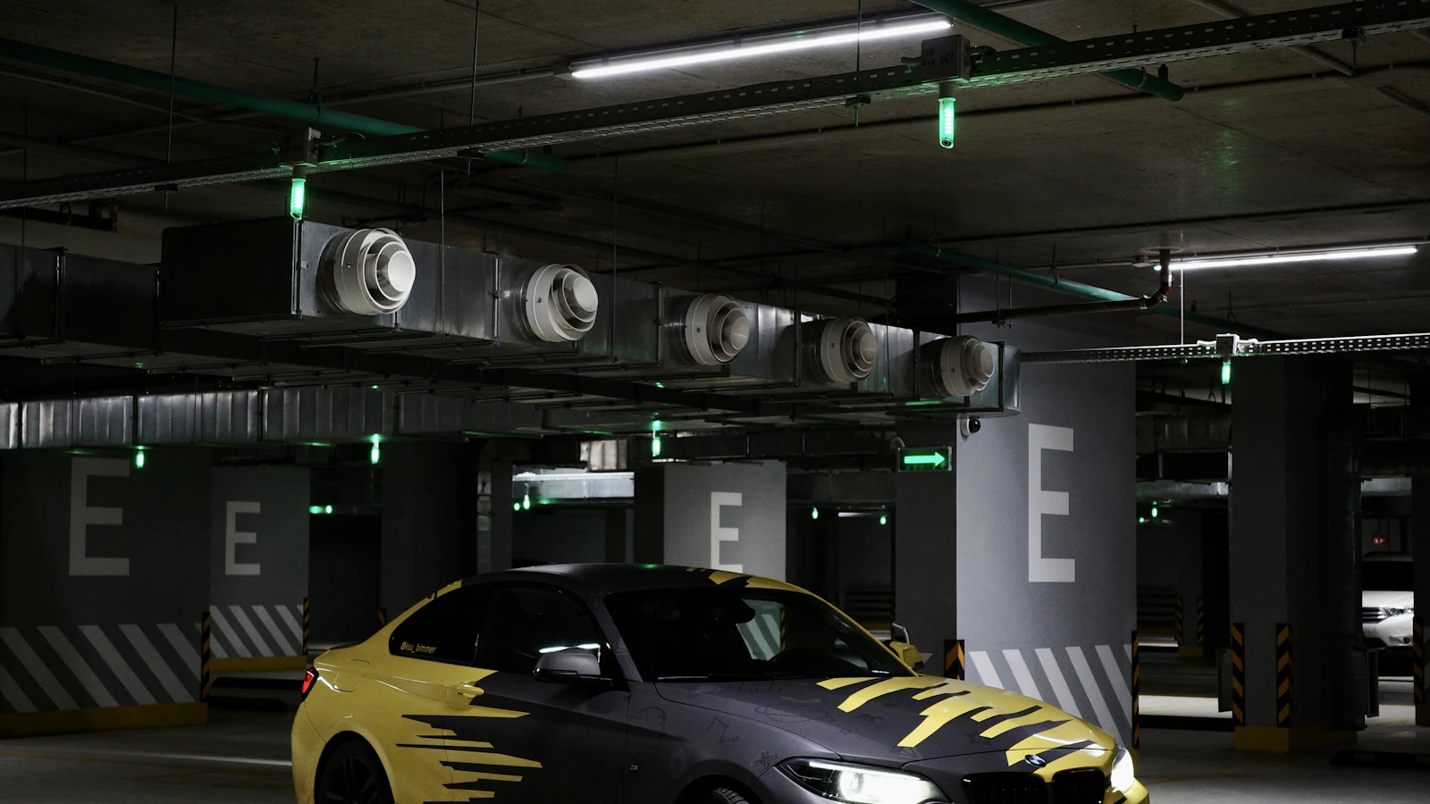 A yellow and black vehicle with graphic markings in a parking garage.