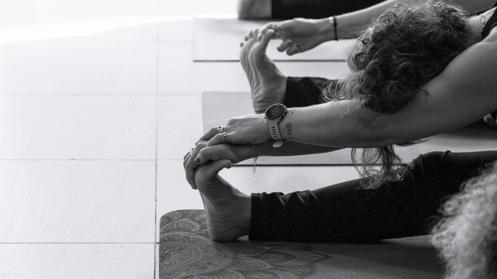 A black-and-white view of people stretching on yoga mats.