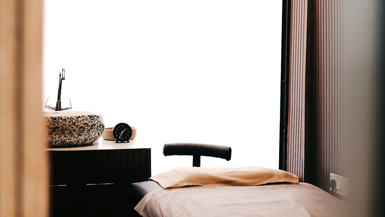 A covered treatment table beside a patterned sink and curtains.