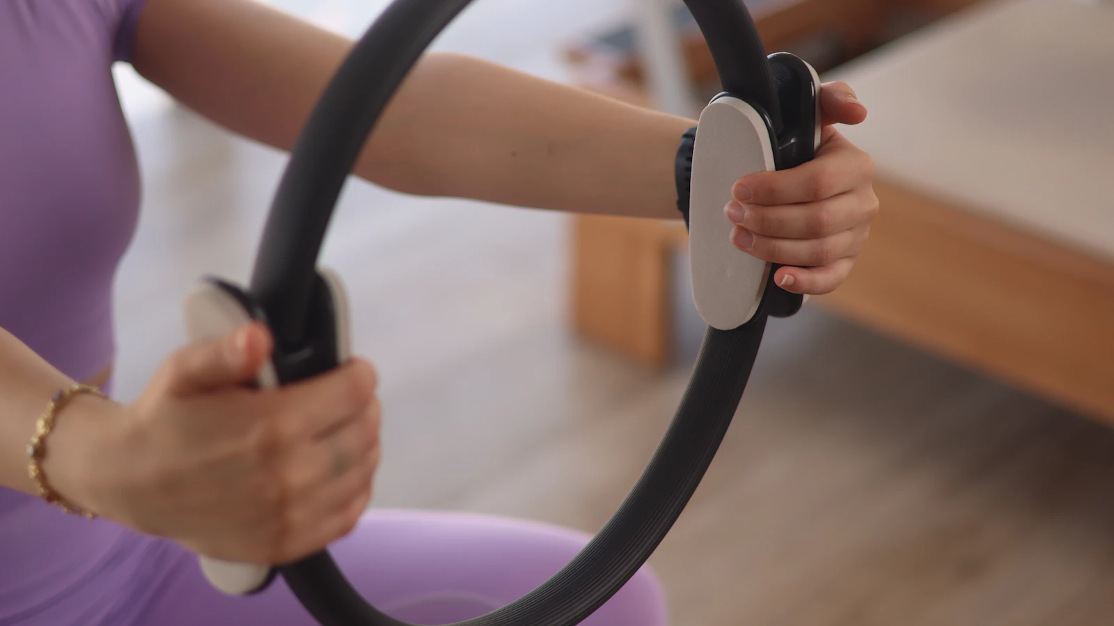 Hands holding a Pilates exercise ring in a studio.
