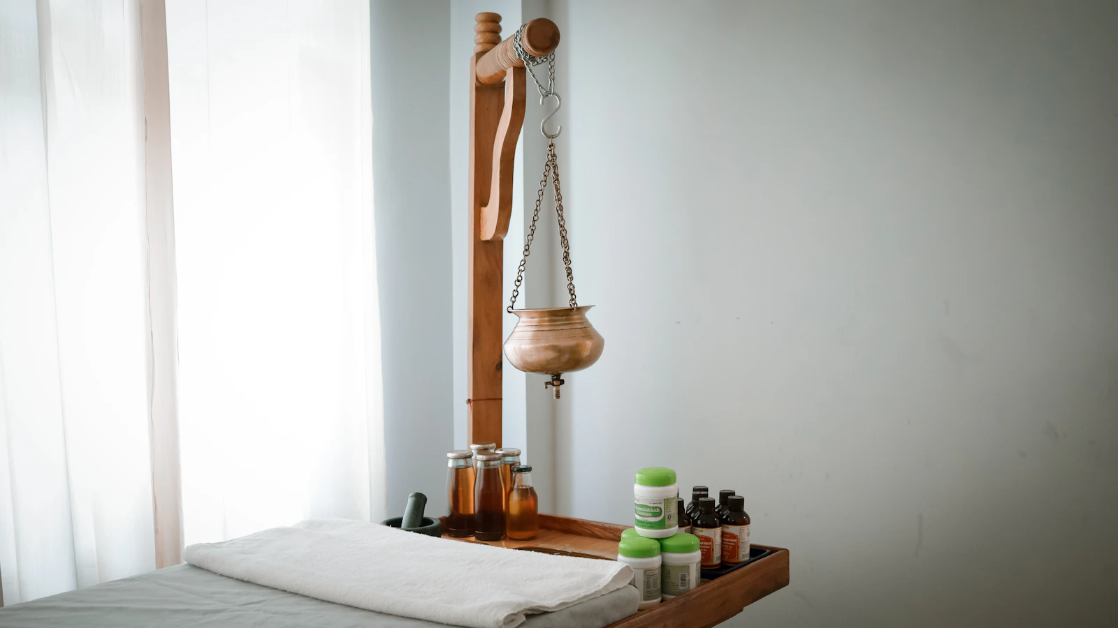 Small bottles and a wooden figure arranged beside a towel in a wellness room.
