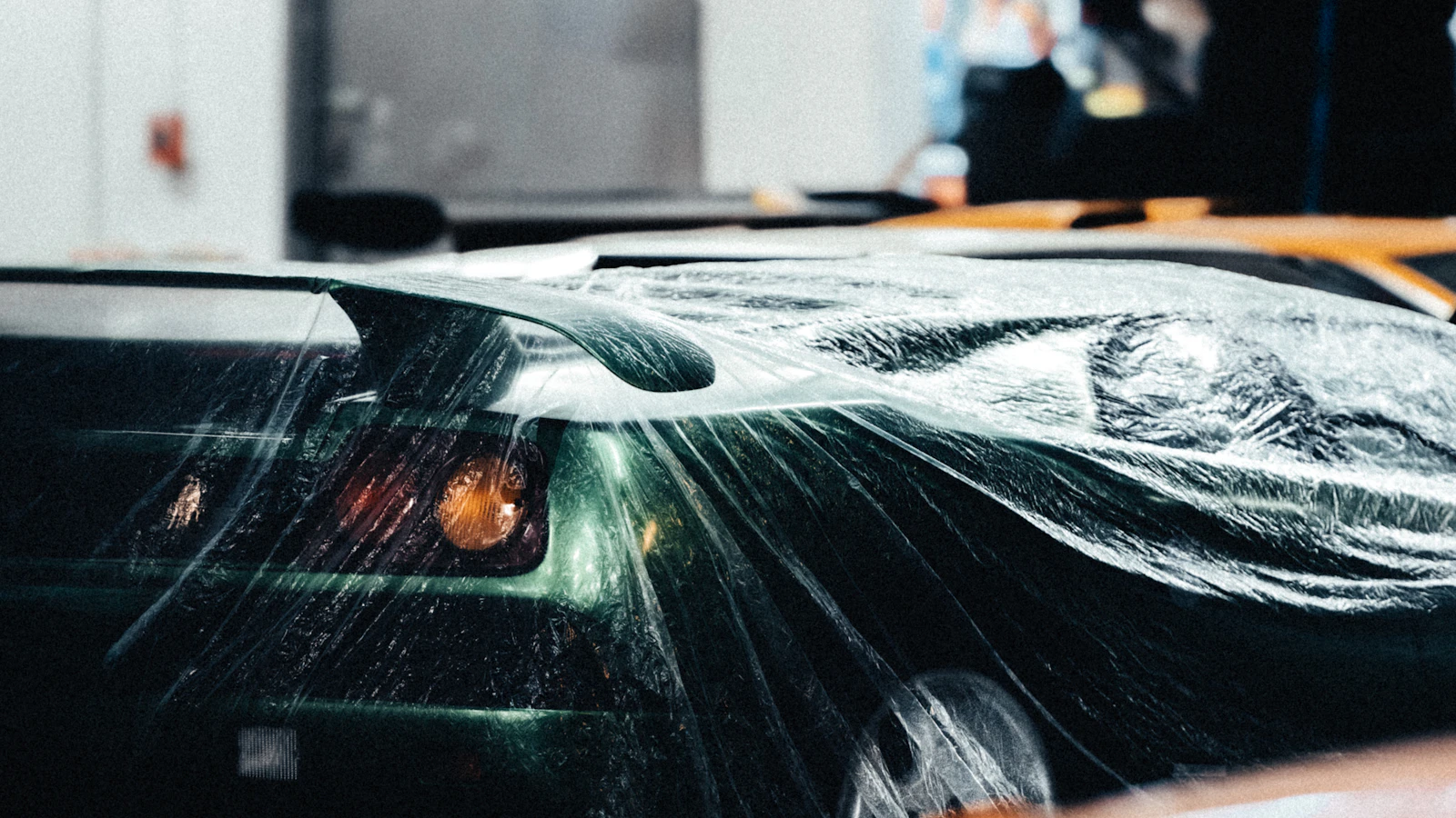 Transparent film stretched across the front of a vehicle in a workshop.