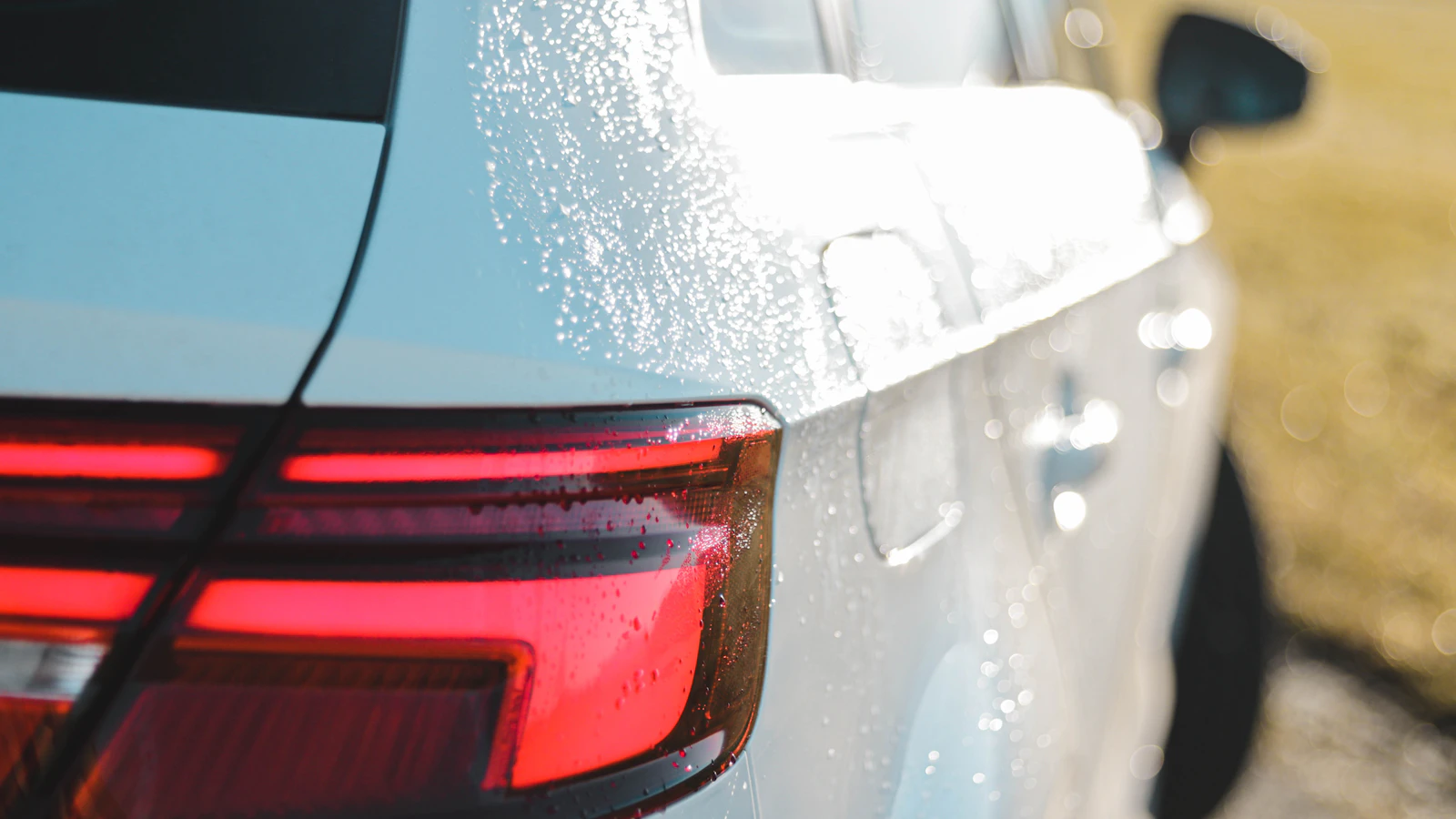 Water droplets on the rear corner and side panel of a white vehicle.