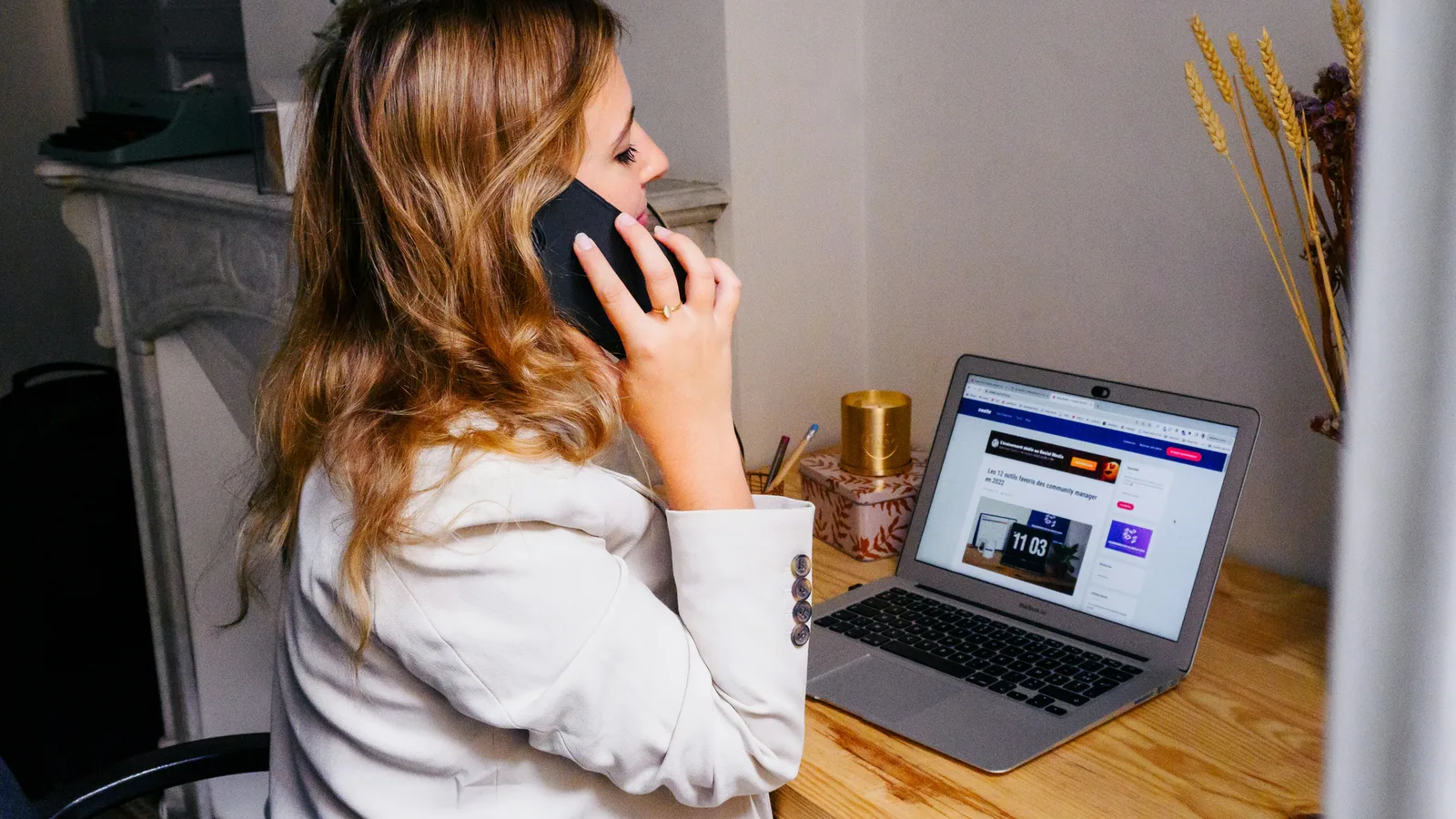 A woman sitting at a desk with a laptop and a phone.