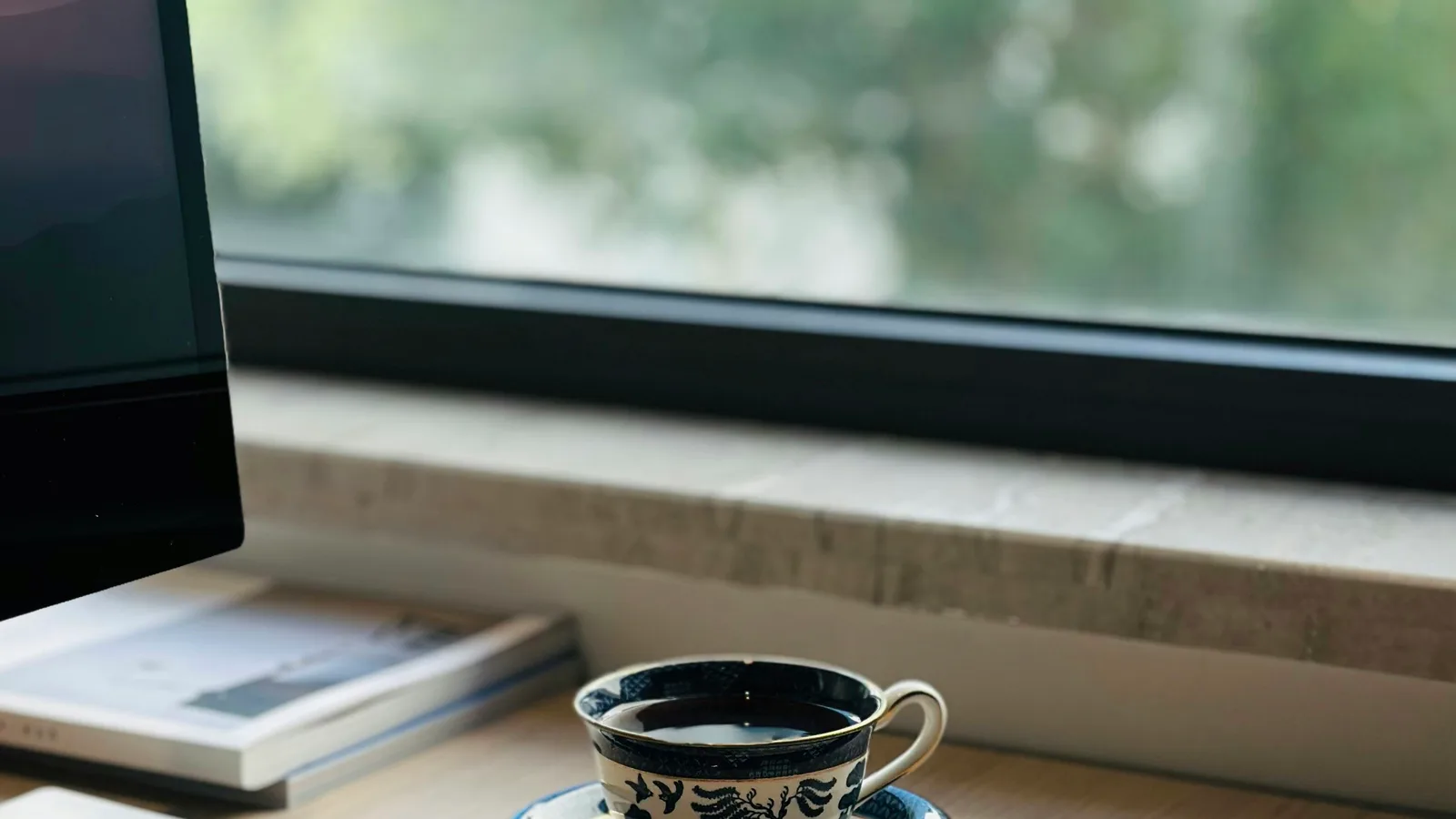 A cup of coffee on a desk by the window.
