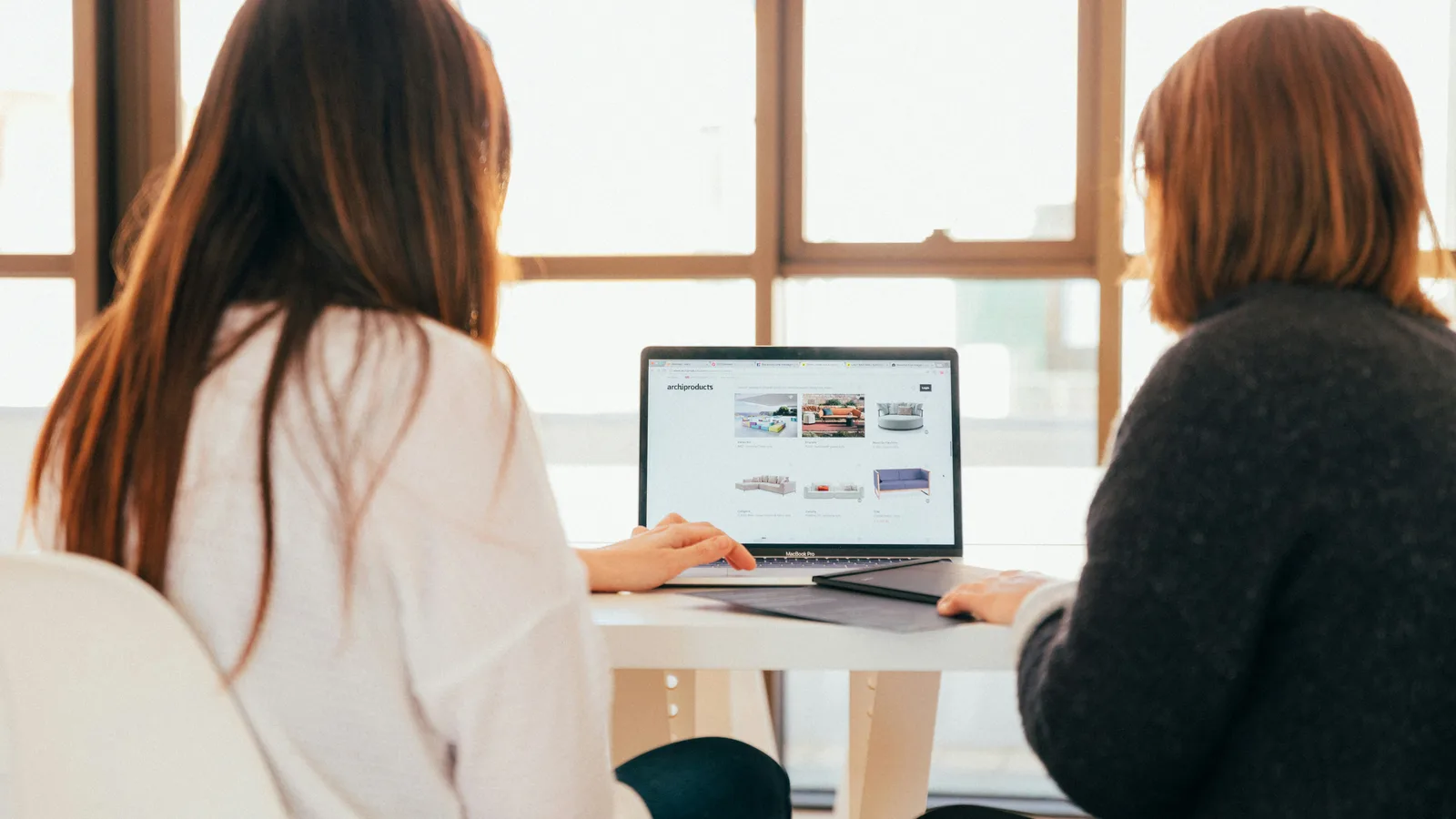 Two women talking while looking at laptop computer.