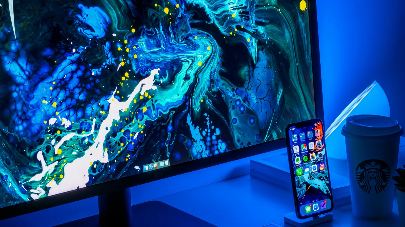 Desktop monitor displaying a blue abstract wallpaper beside a smartphone.
