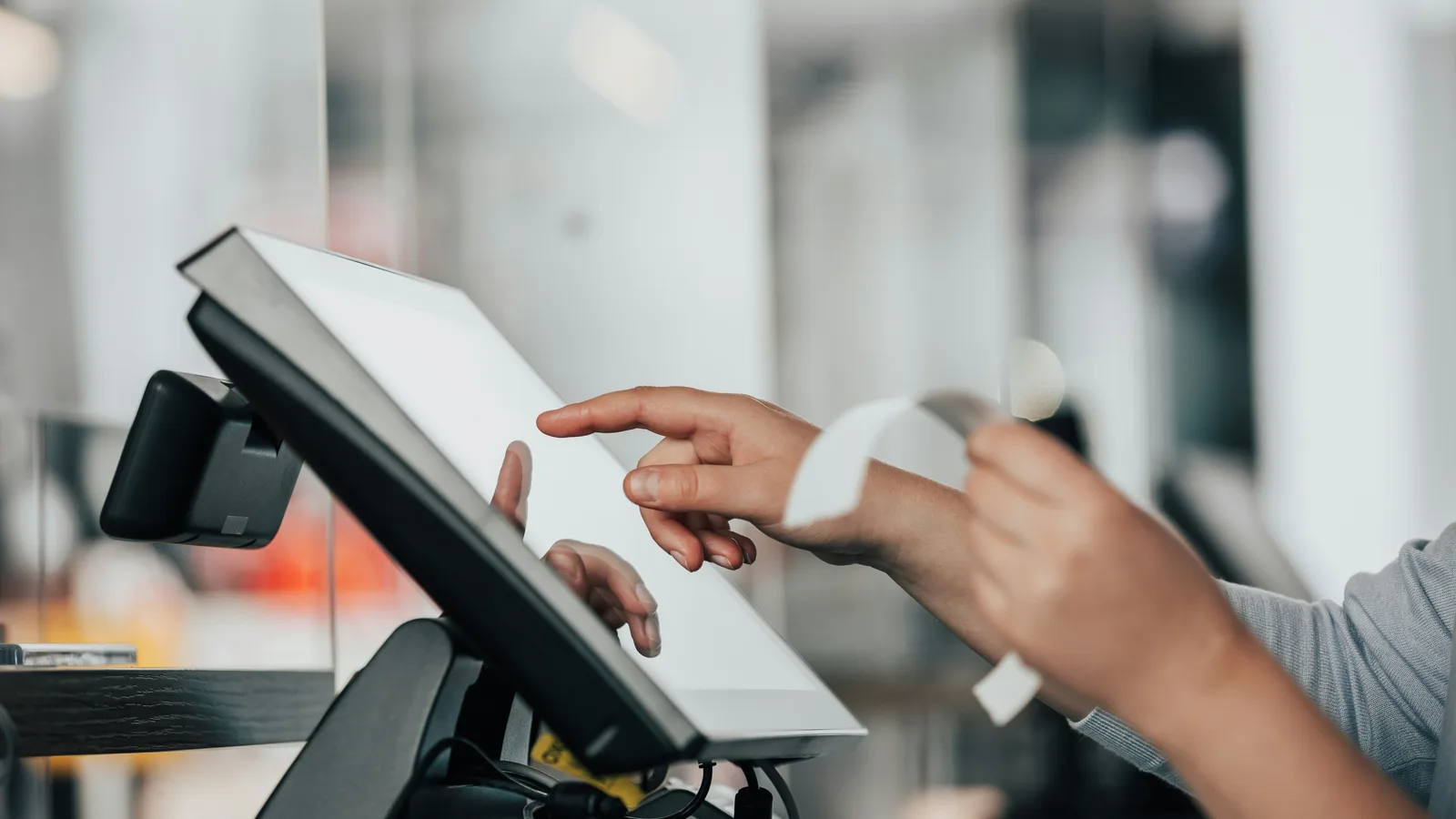 Hands operating a touchscreen point-of-sale terminal.