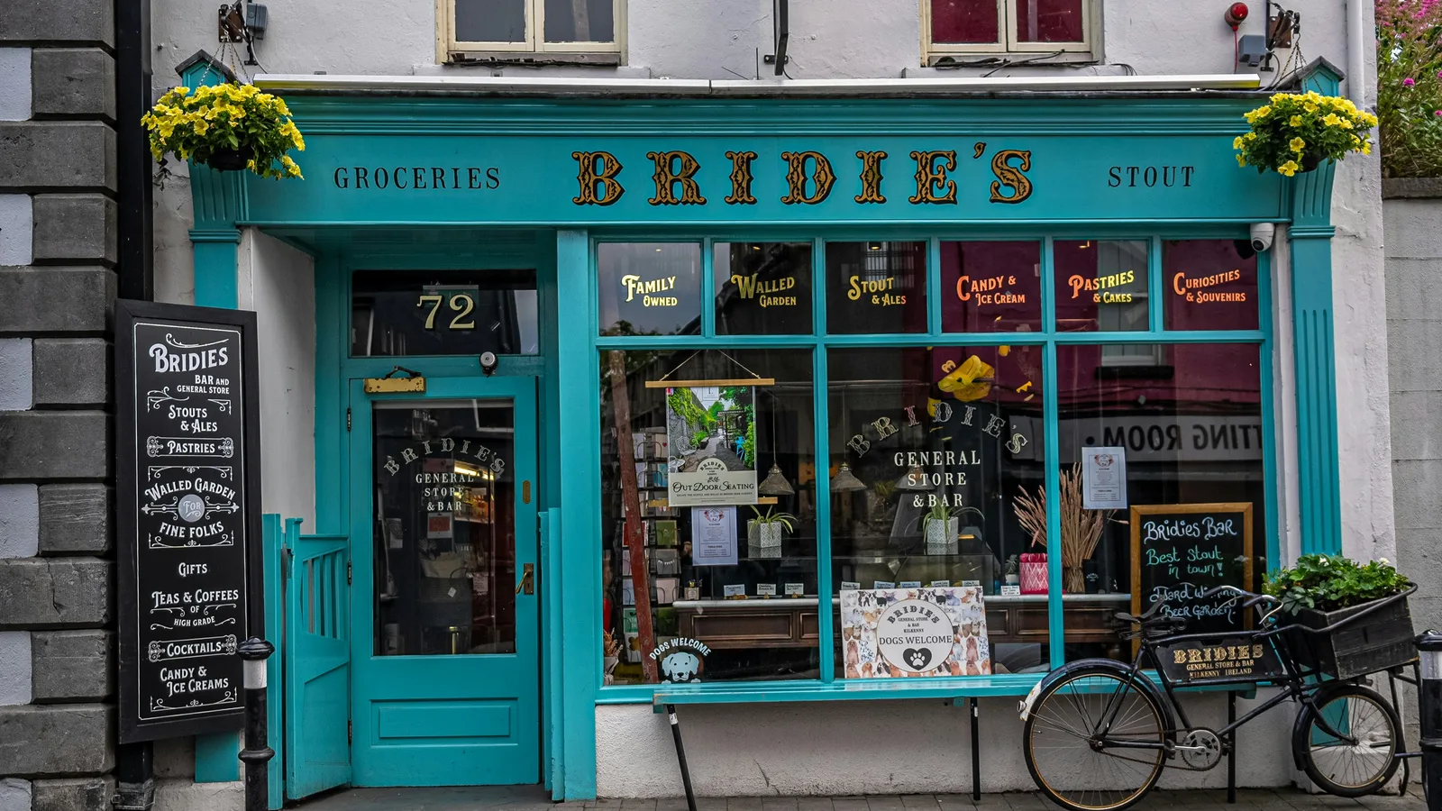 Turquoise shopfront with product displays and a parked bicycle.