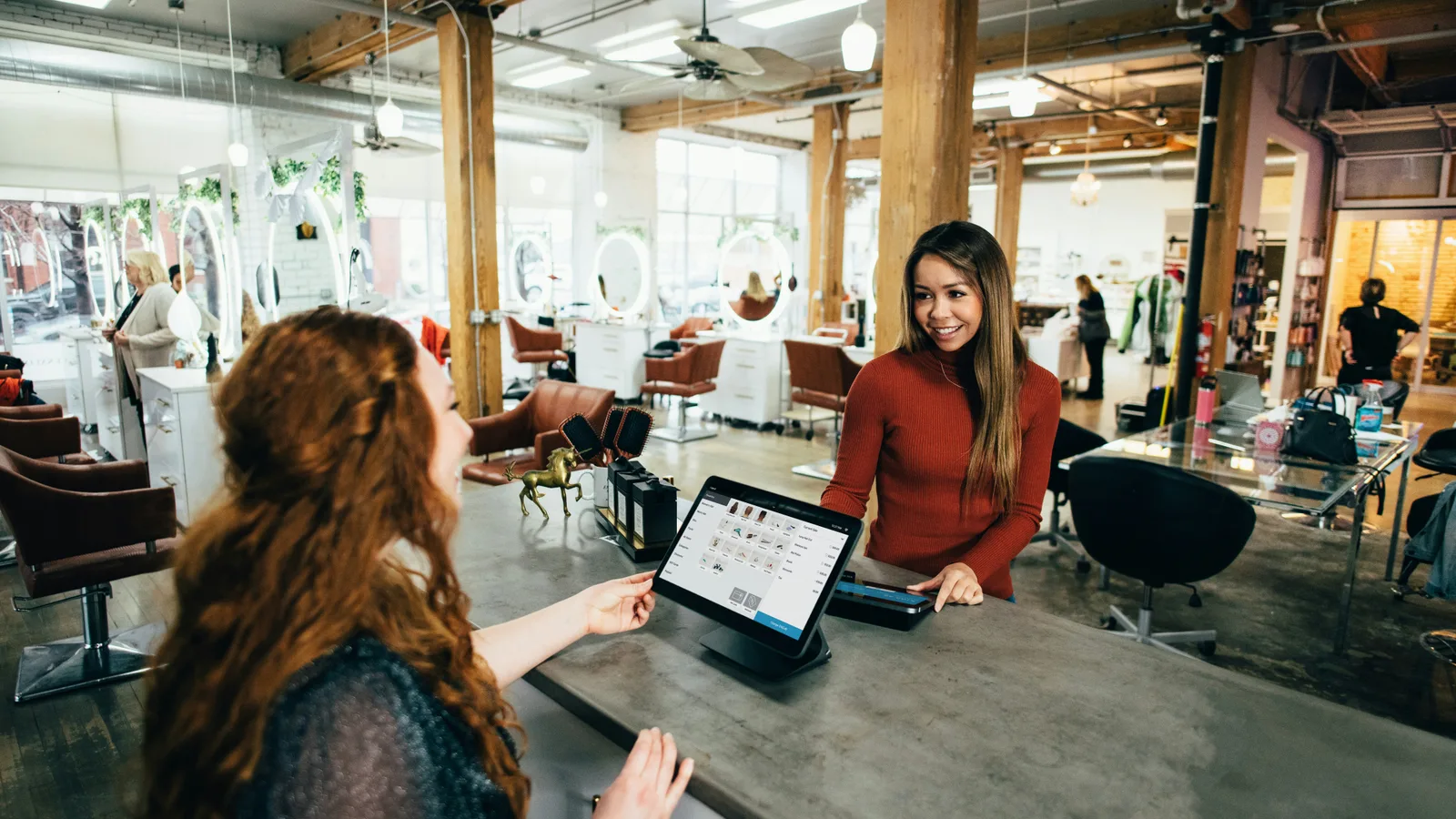 Customer and staff member at a salon checkout counter.