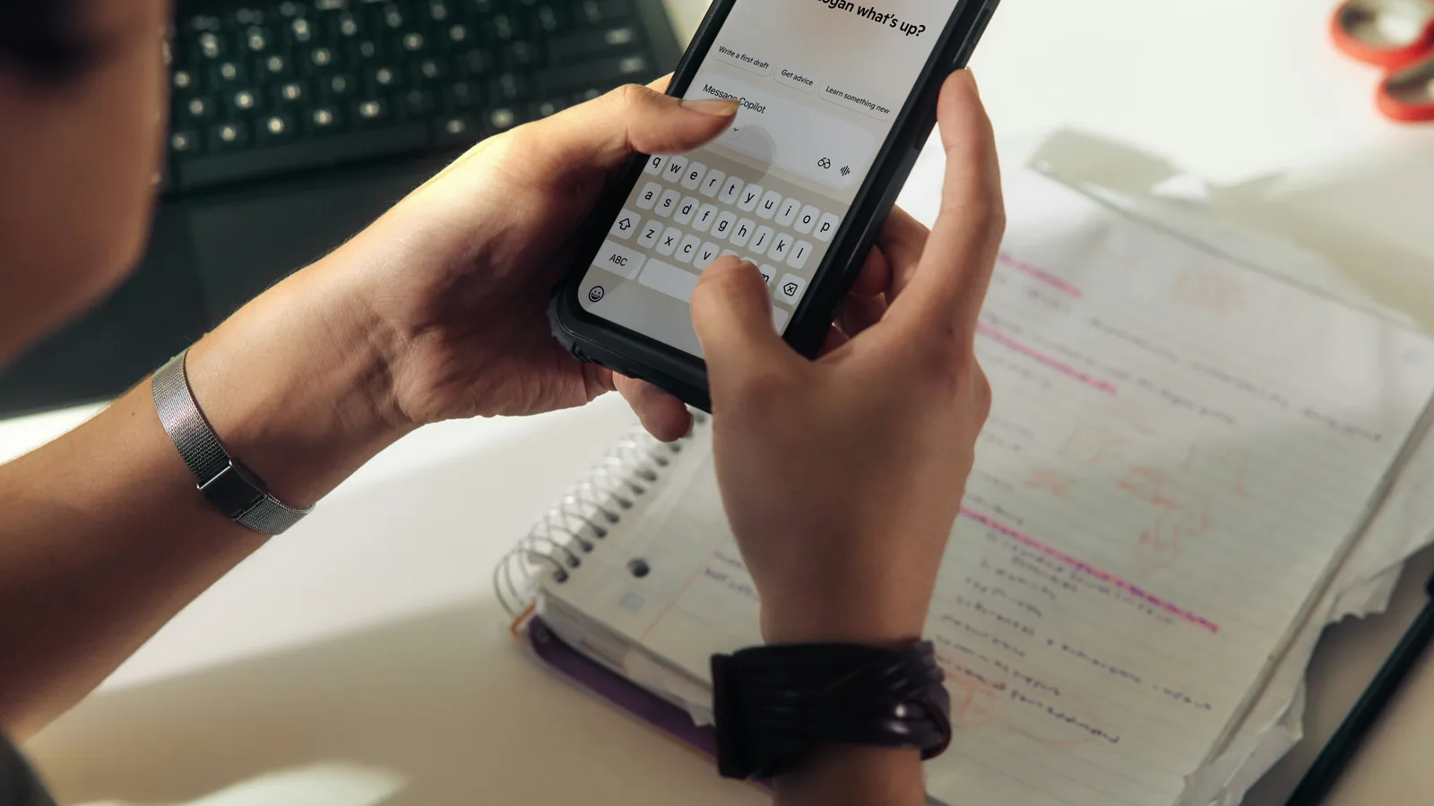 Person using a smartphone over a notebook.