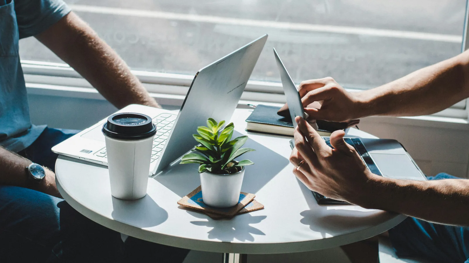 Two people reviewing a laptop and payment card at a small table.