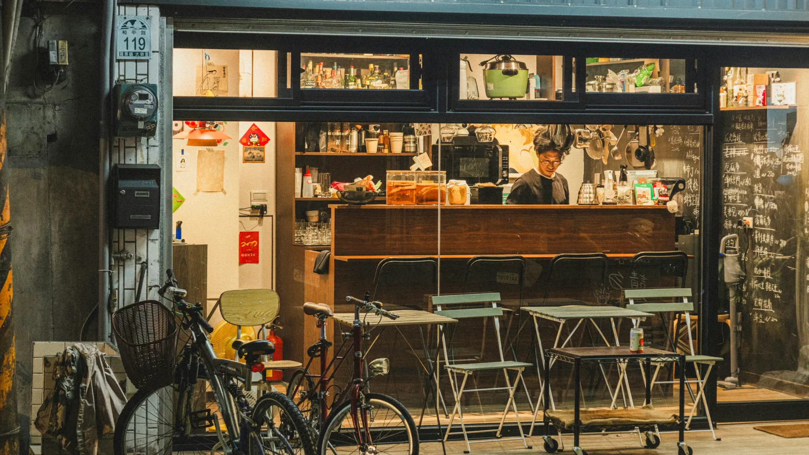 Cafe storefront with outdoor chairs and bicycles.