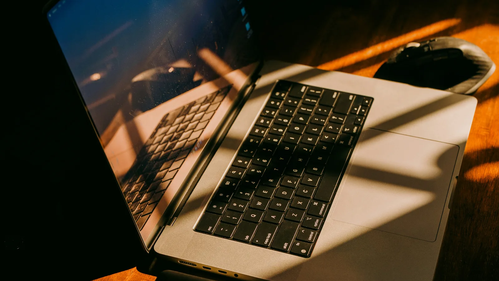 Laptop with sunlight streaming through window blinds.