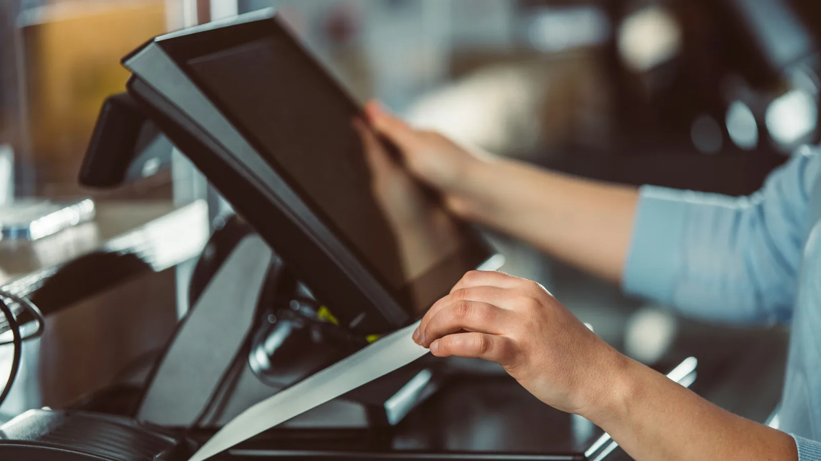 Hands using a touchscreen checkout terminal.
