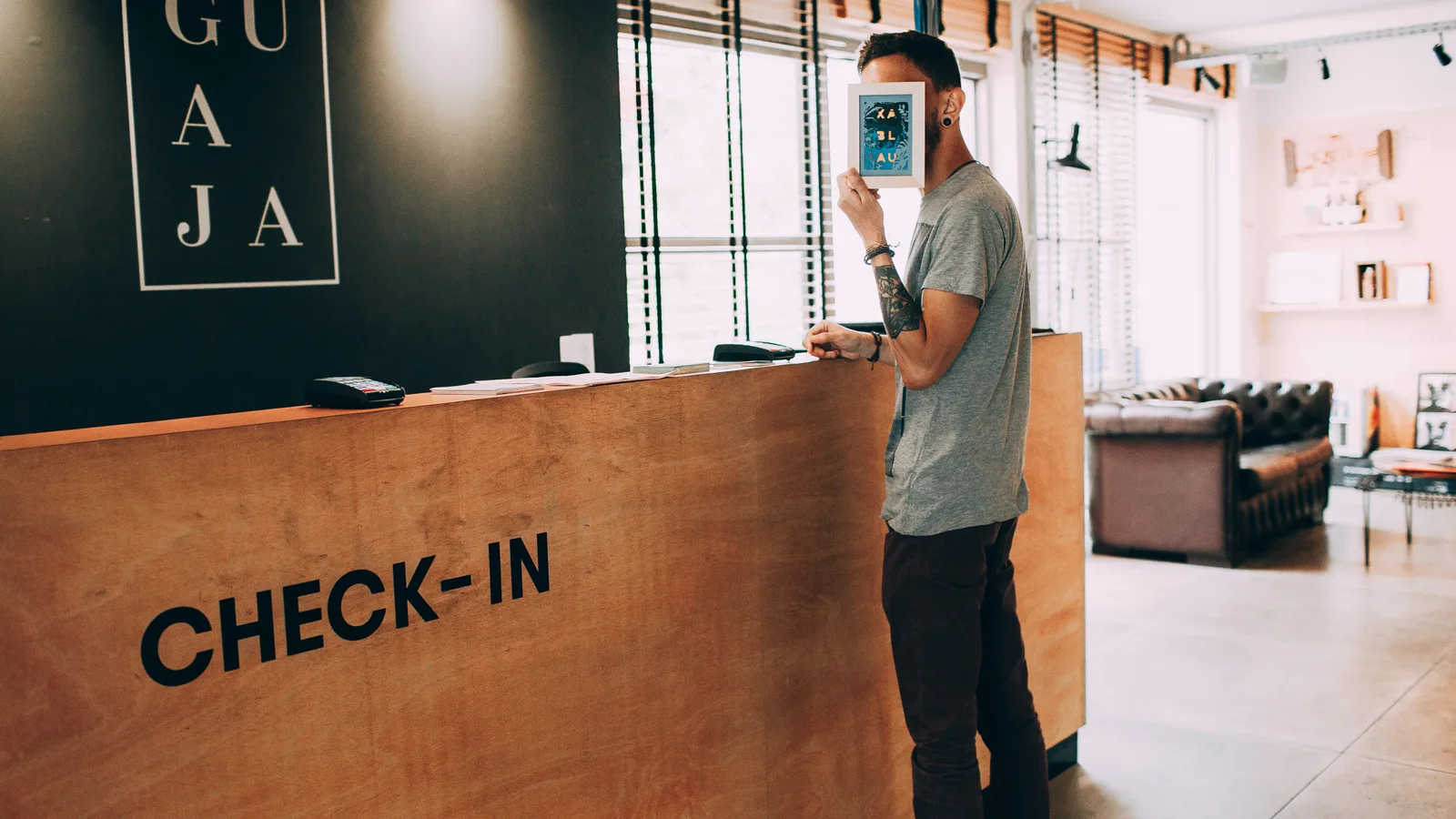 Person holding a smartphone beside a wooden check-in counter.