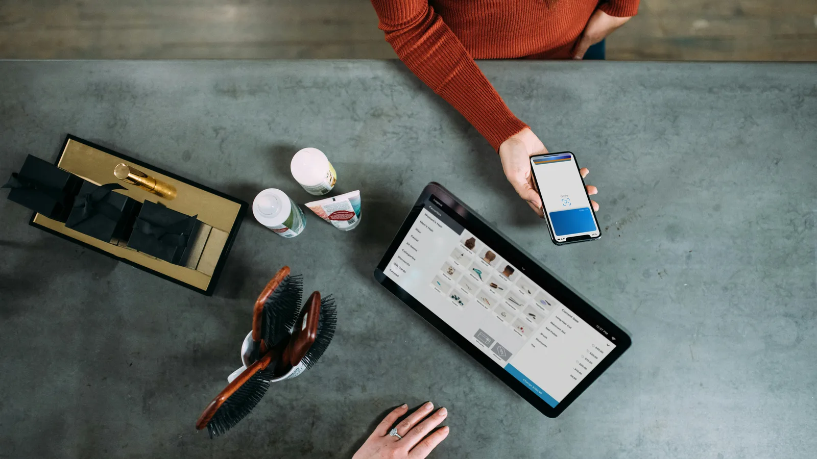 Customer holding a smartphone beside a countertop checkout tablet.