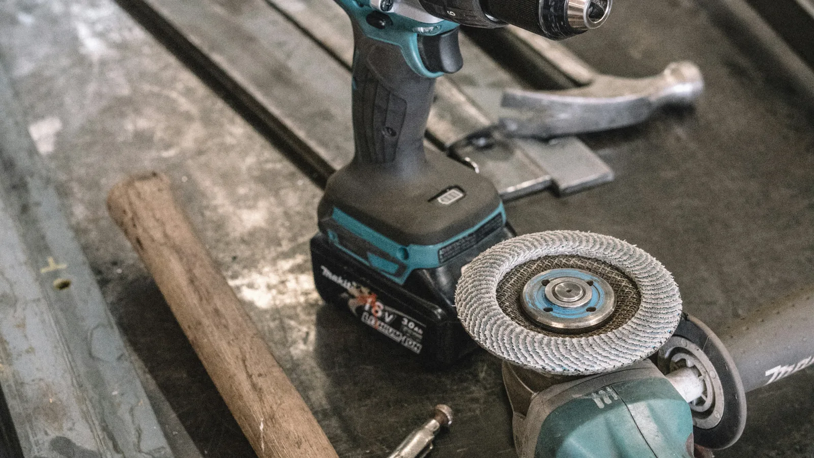 Cordless drill and angle grinder on a workbench.