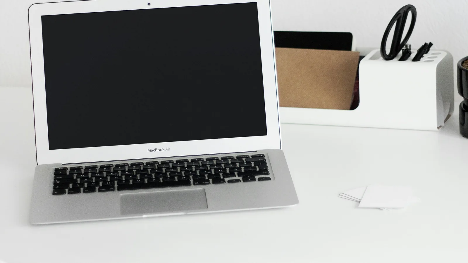 Open laptop with a dark screen on a white desk.