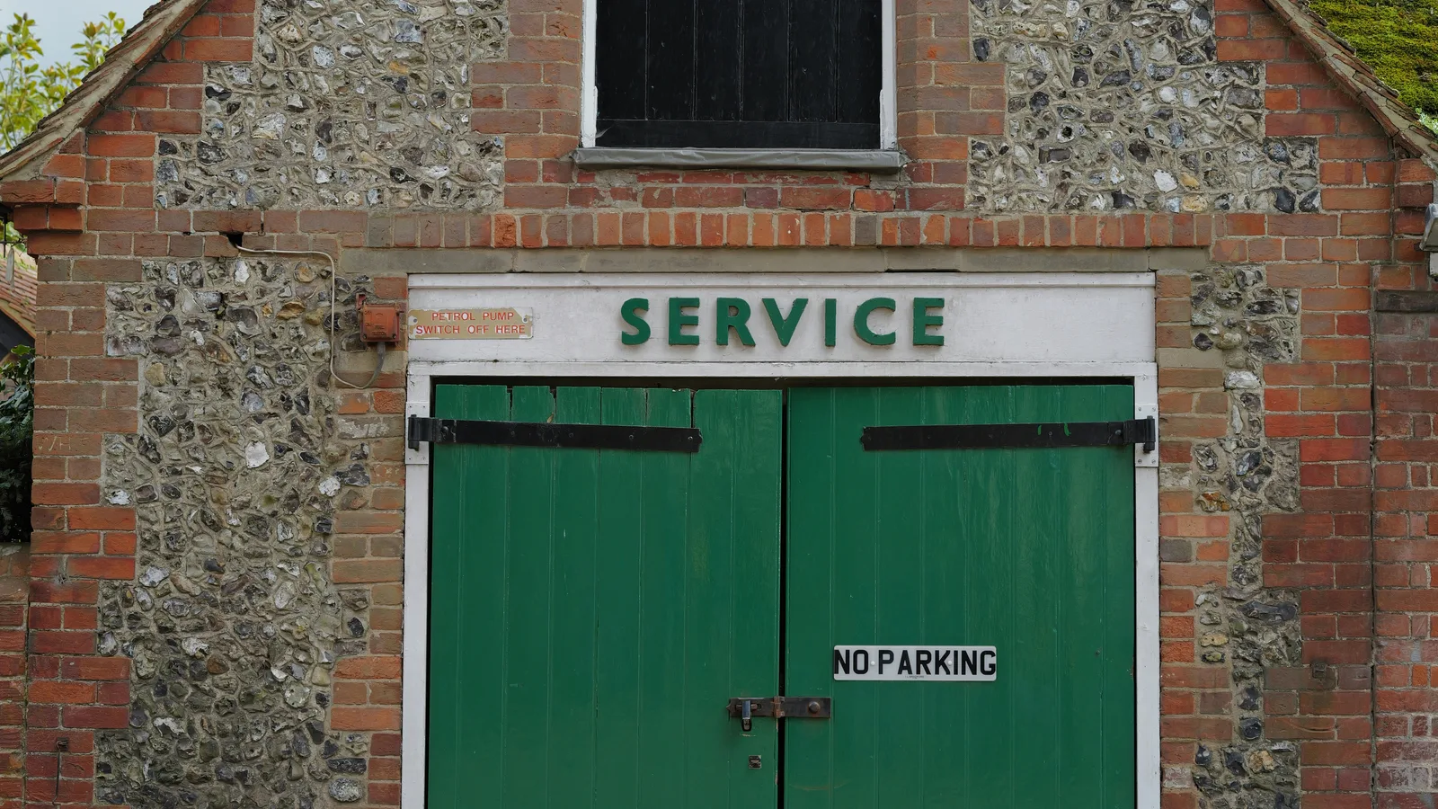 Brick building with green double doors and "service" sign.