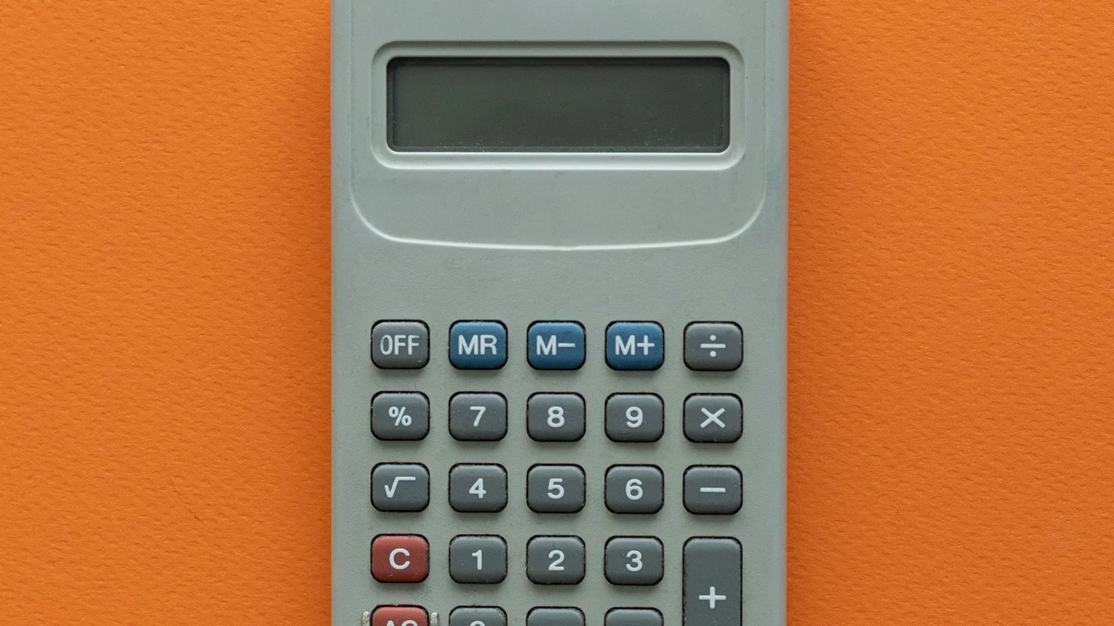 Grey calculator on an orange surface.