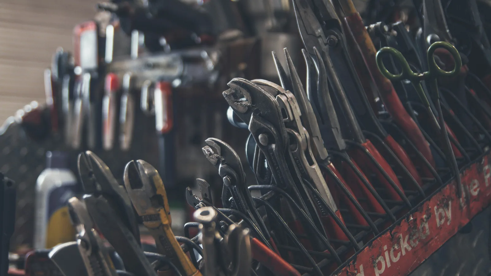 Pliers, wrenches and other hand tools arranged in a rack.