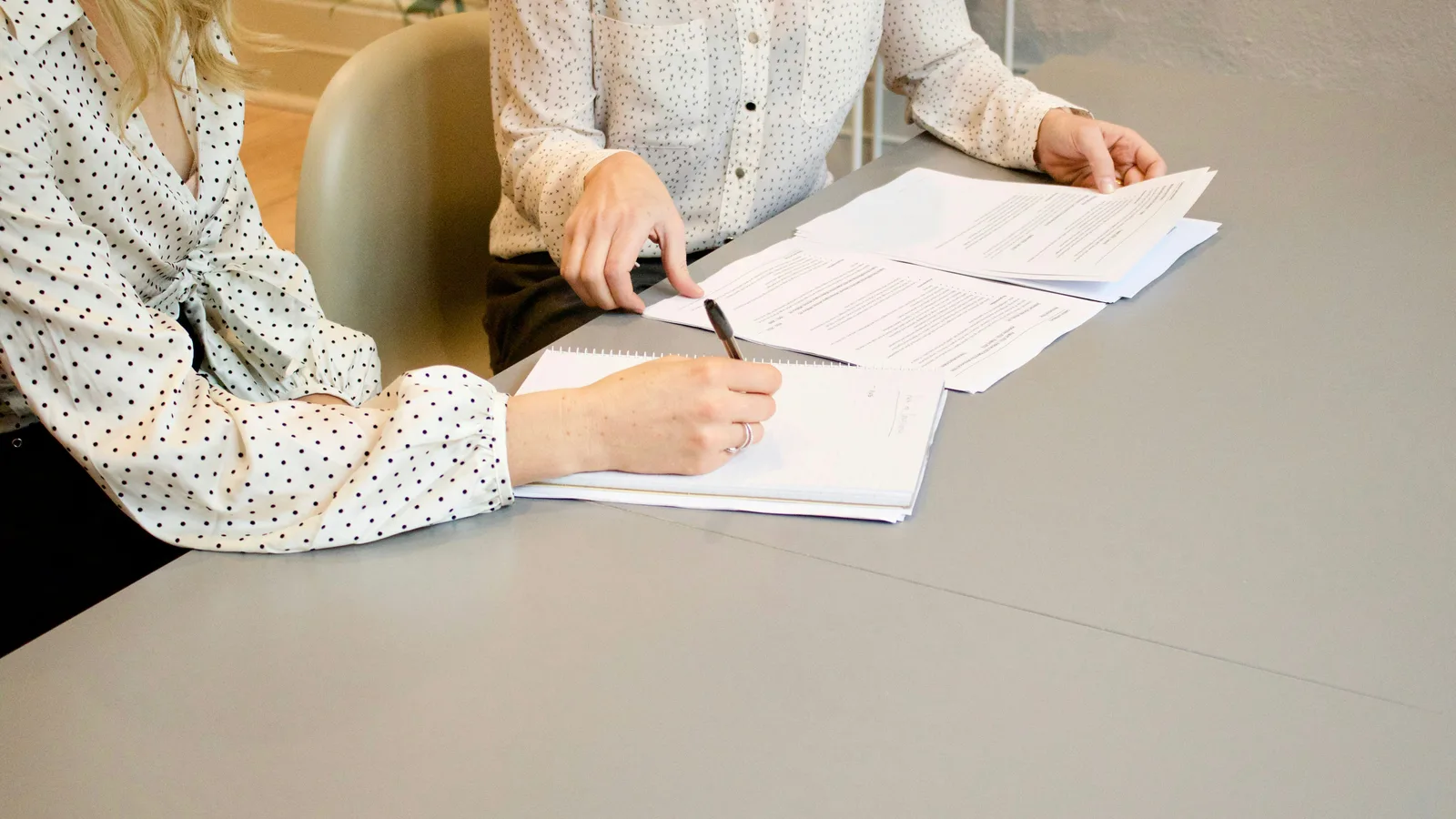 Two people reviewing and marking printed documents.